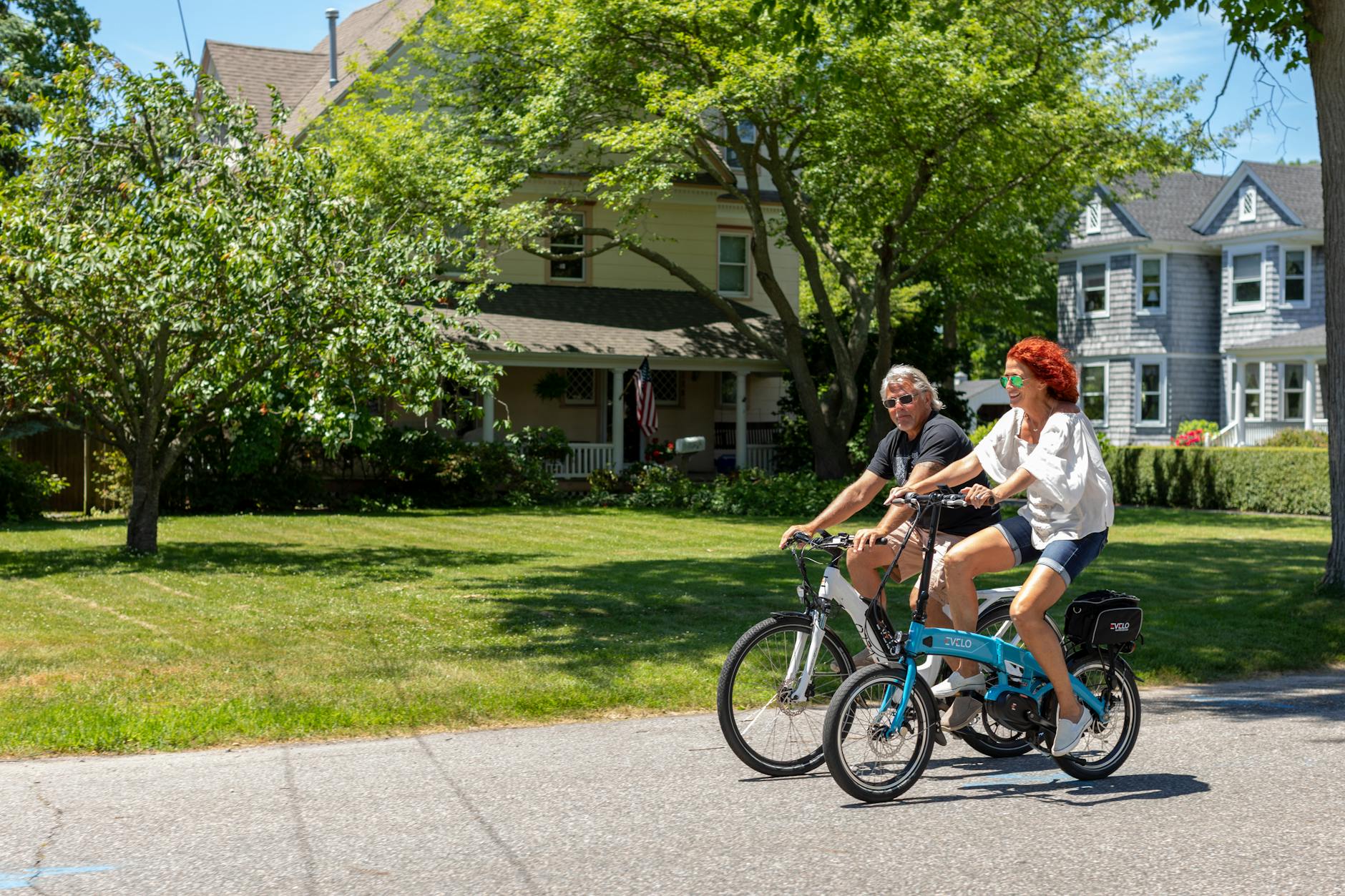 A couple riding electric bikes on a sunny day in Patchogue, NY, enjoying outdoor leisure.