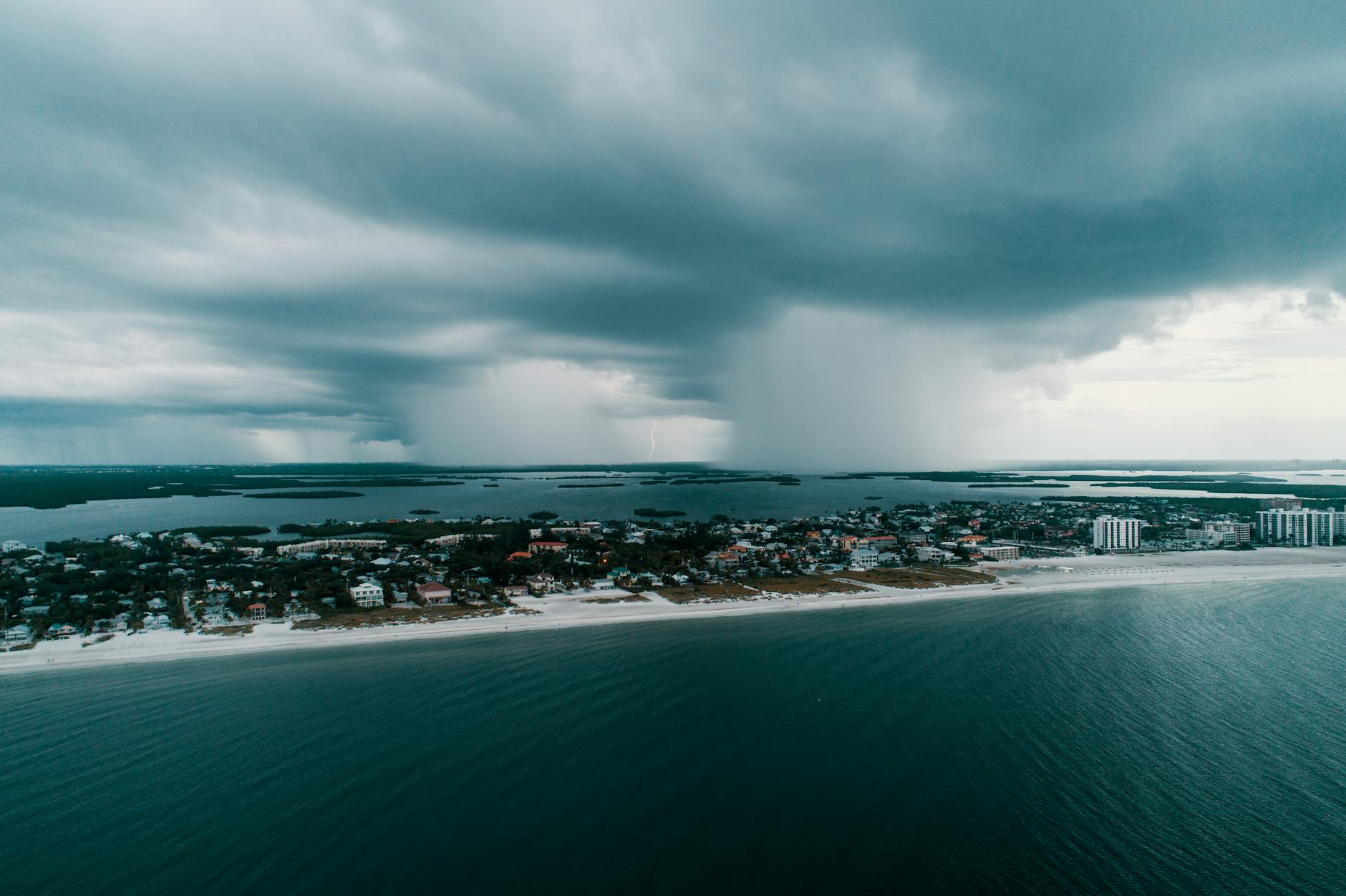 A stunning aerial view capturing a storm approaching an island village along the coast.